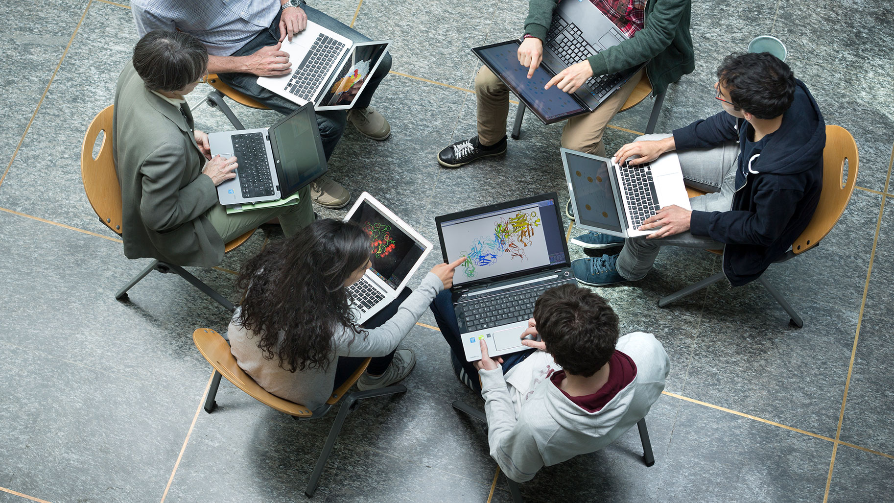 Groupe de personnes assises en cercle avec des ordinateurs portable