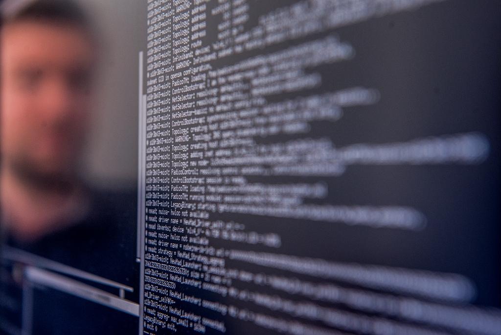 Reflet d'un homme dans un écran lié rempli de lignes de code